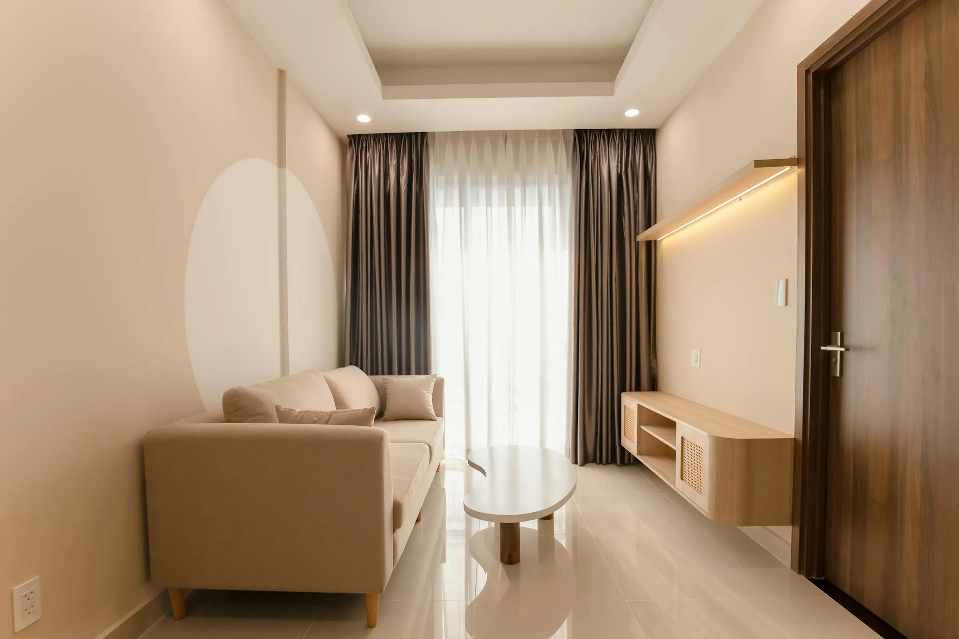 A minimalist living room with a beige sofa, modern table, and soft lighting.