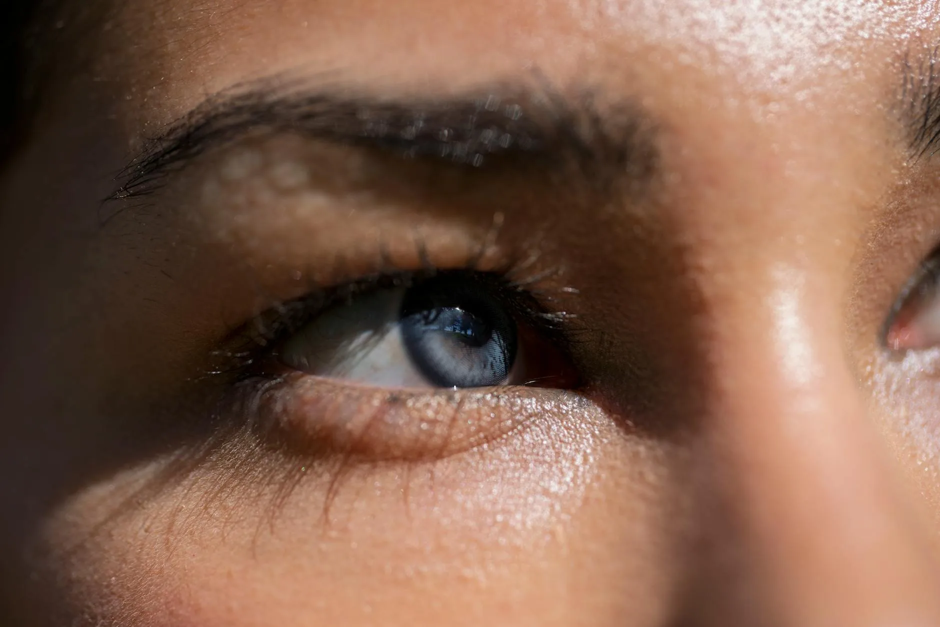 A detailed close-up of a human eye with blue iris reflecting sunlight, showcasing emotions.